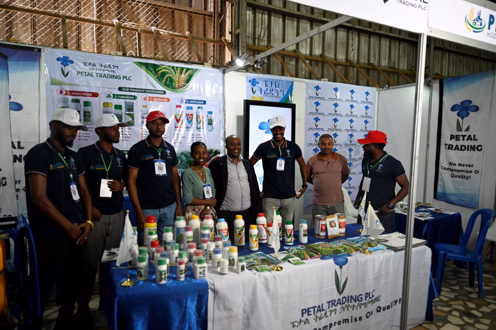 Exhibitors and visitors gathered around a stand displaying bottled agricultural inputs.