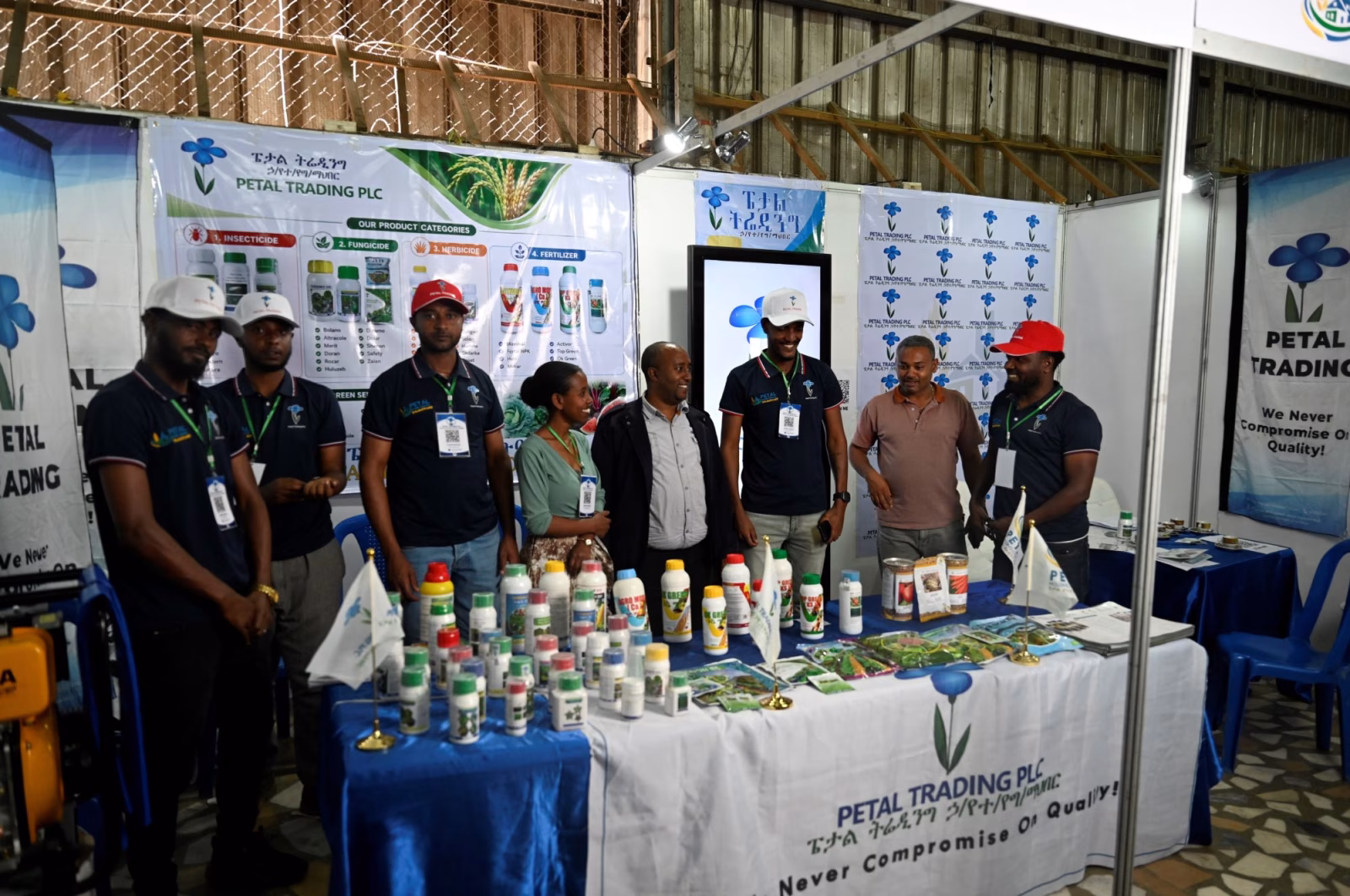 A group of exhibitors standing behind a table of crop protection products at their stand.